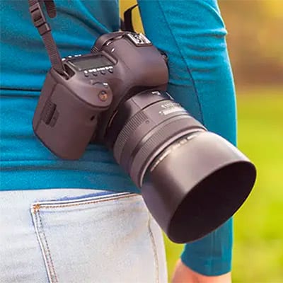 eine Frau hat bei einem Fotokurs in Erfurt eine Kamera über der Schulter - Werbung für einen Gutschein für einen Fotoworksho p